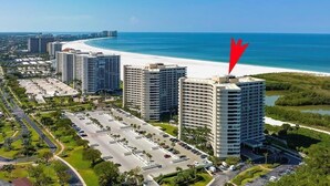 A high-rise hotel with a parking lot, adjacent to a beach and ocean. - Beachfront 2BR condo with pool, WiFi, and heated pool on Marco Island. (Marco Island)