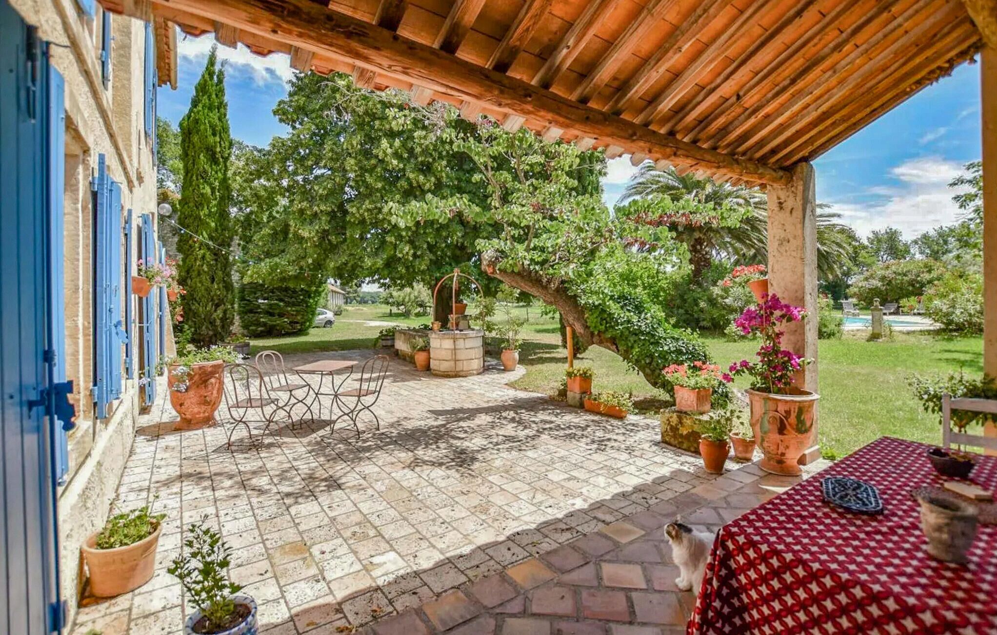 Un patio cubierto con suelo de piedra, mobiliario exterior y plantas en macetas.