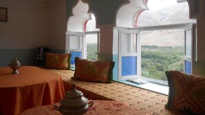 A room with a dining table, chairs, and a view of a mountainous landscape through arched windows. - Ighrem Le Grenier (Tabant)