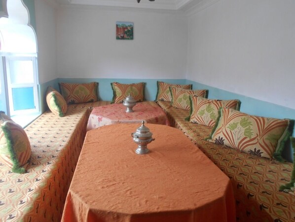 Una habitación con una larga mesa y dos sofás, cada uno con cojines estampados.