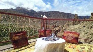 A table set with a tray, glasses, and a candle, overlooking a mountainous landscape. - Ighrem Le Grenier (Tabant)