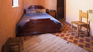 A bedroom with a wooden bed, a chair, a small table, and a window. - Ighrem Le Grenier (Tabant)