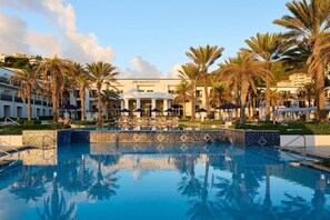 A JW Marriott hotel with a swimming pool surrounded by palm trees and lounge chairs.