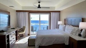 Ein Hotelzimmer mit einem großen Bett, einem Schreibtisch, einem Stuhl und Blick aufs Meer.