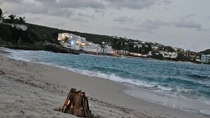 Ein Strand mit einer Holzkonstruktion, Wellen und einer Küstenstadt im Hintergrund.
