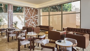 A spacious indoor area with multiple seating arrangements, including sofas and chairs, and large windows providing natural light. - The View - Saint Georges Hotel (Beirut)