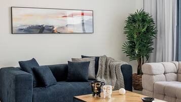 A modern living room with a dark grey sofa, a wooden coffee table, and a large abstract painting on the wall.
