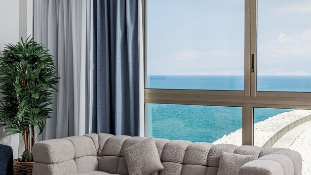 A modern living room with a large window offering a view of the sea. - The View - Saint Georges Hotel (Beirut)