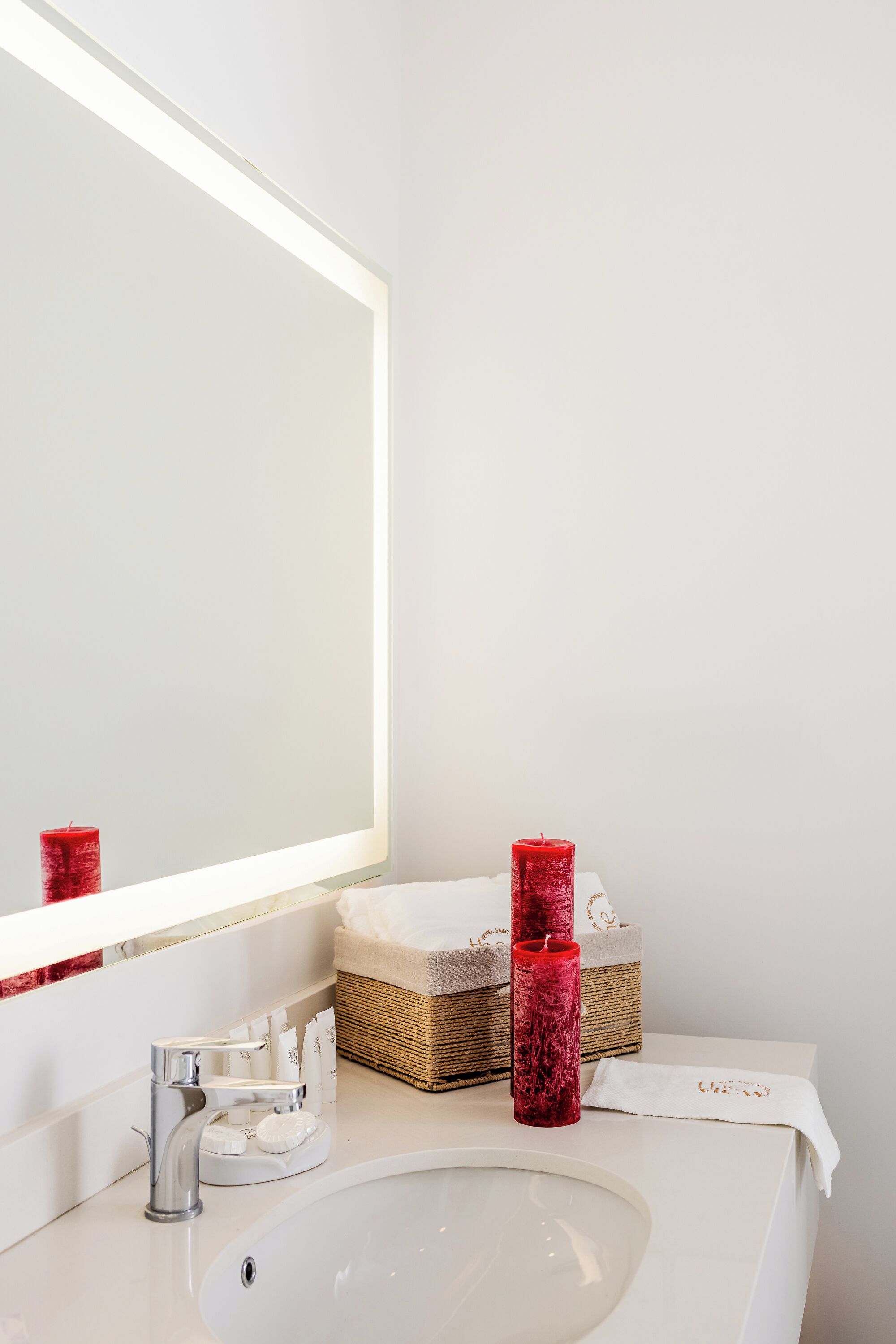 A bathroom with a white sink, a mirror, and a red candle.