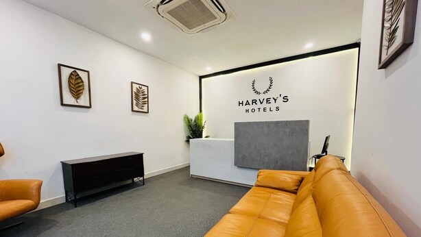 A reception area with a reception desk, a sofa, a bench, and framed artwork on the walls. - Harvey's Hotels (Hyderabad)