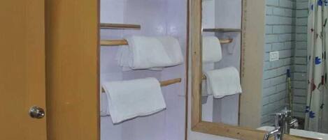 A bathroom with a wooden vanity, a white sink, and a mirror with a white towel hanging on the wall.