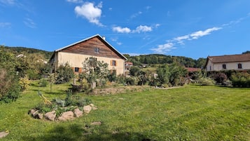 A rural house with a sloped roof, surrounded by a well-maintained lawn and trees.