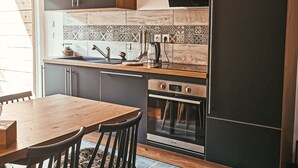 A modern kitchen with a wooden table, dark cabinets, and a built-in oven.