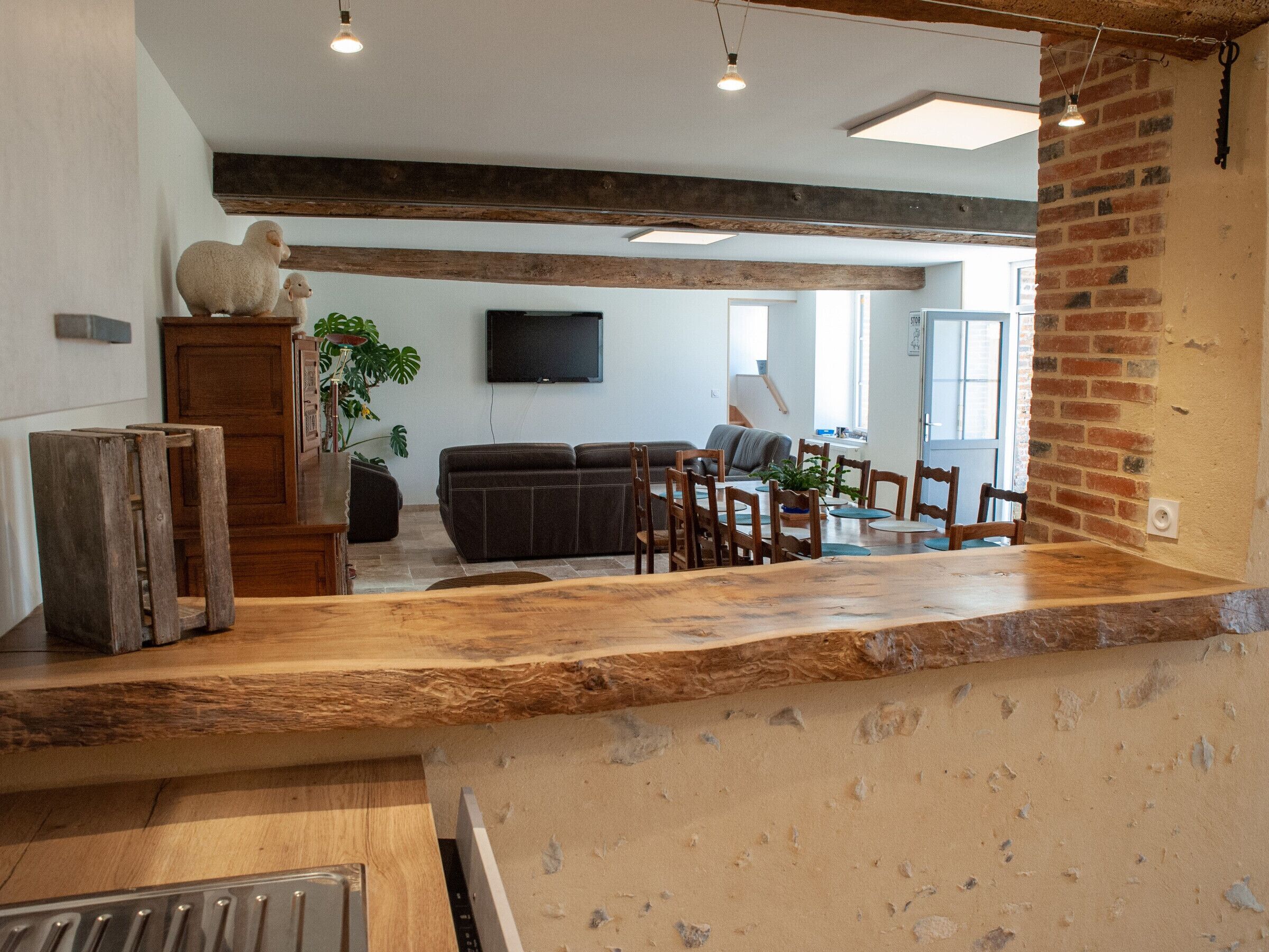 Un interior rústico con paredes de ladrillo visto, una barra de madera, un sofá y una zona de comedor con sillas.