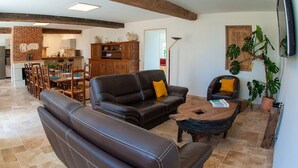 Amplia sala de estar con sofá de cuero, una mesa de centro de madera y comedor con chimenea de ladrillo.