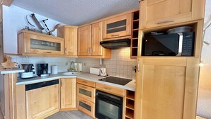 Une cuisine de taille réduite, dotée de meubles en bois, d’un four à micro-ondes, d’un lave-vaisselle et d’une cuisinière.