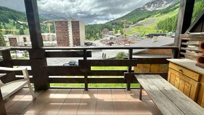 Une terrasse en bois offrant une vue sur un paysage montagneux, un chantier de construction et des bâtiments situés au loin.