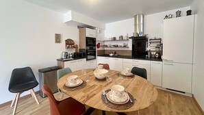 Une cuisine compacte dotée d’appareils électroménagers modernes, une table à manger pour quatre personnes et un petit coin cuisine.