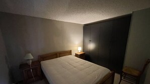 Une chambre à coucher comprenant un lit, une table de chevet, une lampe, une armoire et une chaise.