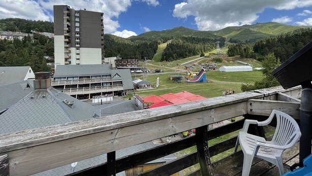 Vue d’une station de ski avec un télésiège, des bâtiments et un paysage montagneux.