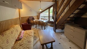 Une pièce chaleureuse avec un plafond en bois, un canapé, une table à manger et un escalier.