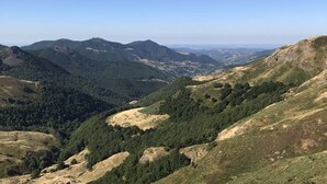 Un paysage montagneux avec une vallée et des collines à l’horizon.