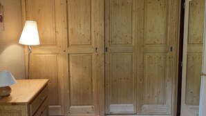 A room with wooden double doors, a lamp on a wooden nightstand, and a mirror on the wall.