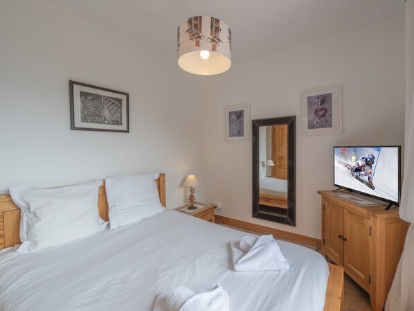 Ett hotellrum med en stor säng, en tv, en spegel och inramade tavlor på väggen.