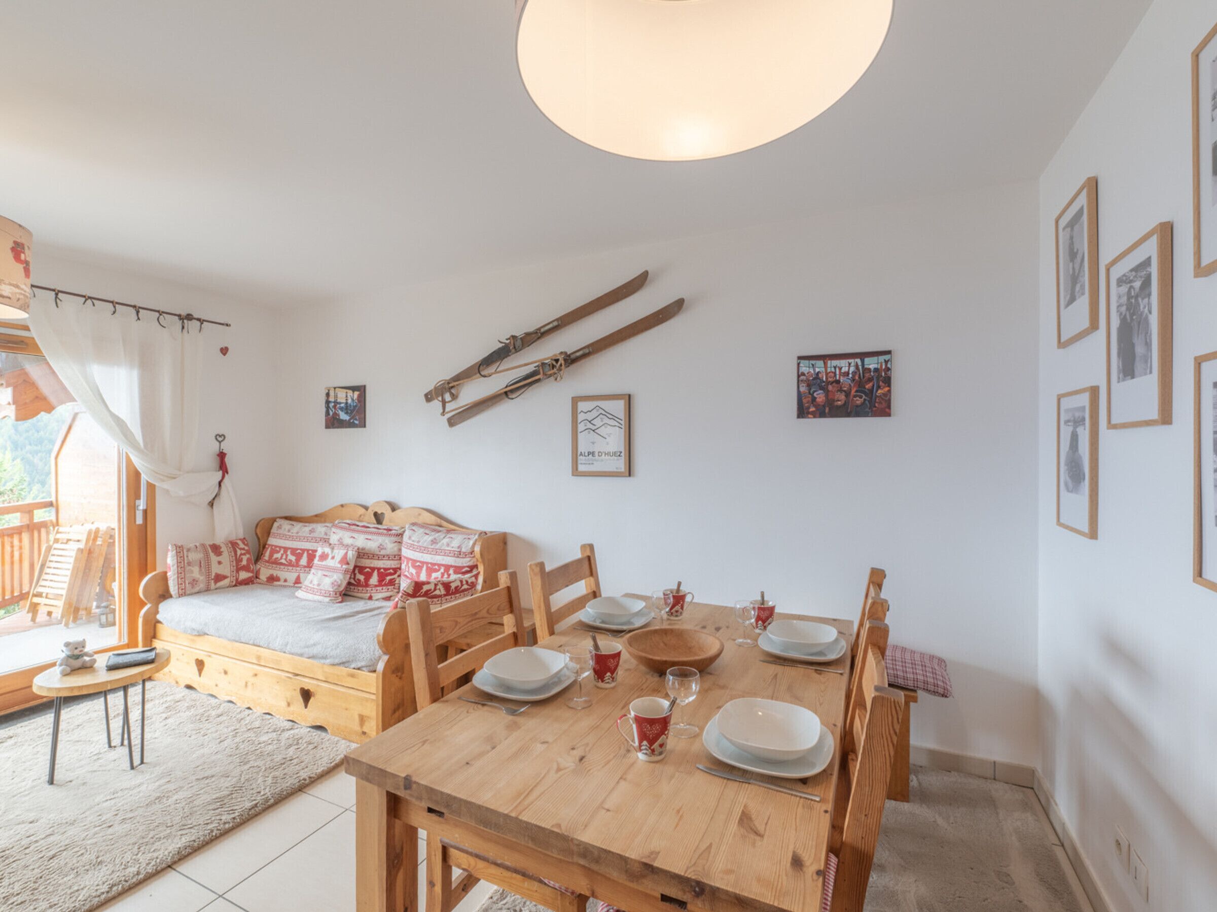 Une pièce chaleureuse avec un lit en bois, une table à manger dressée avec des assiettes et des verres, et un porte-skis fixé au mur.