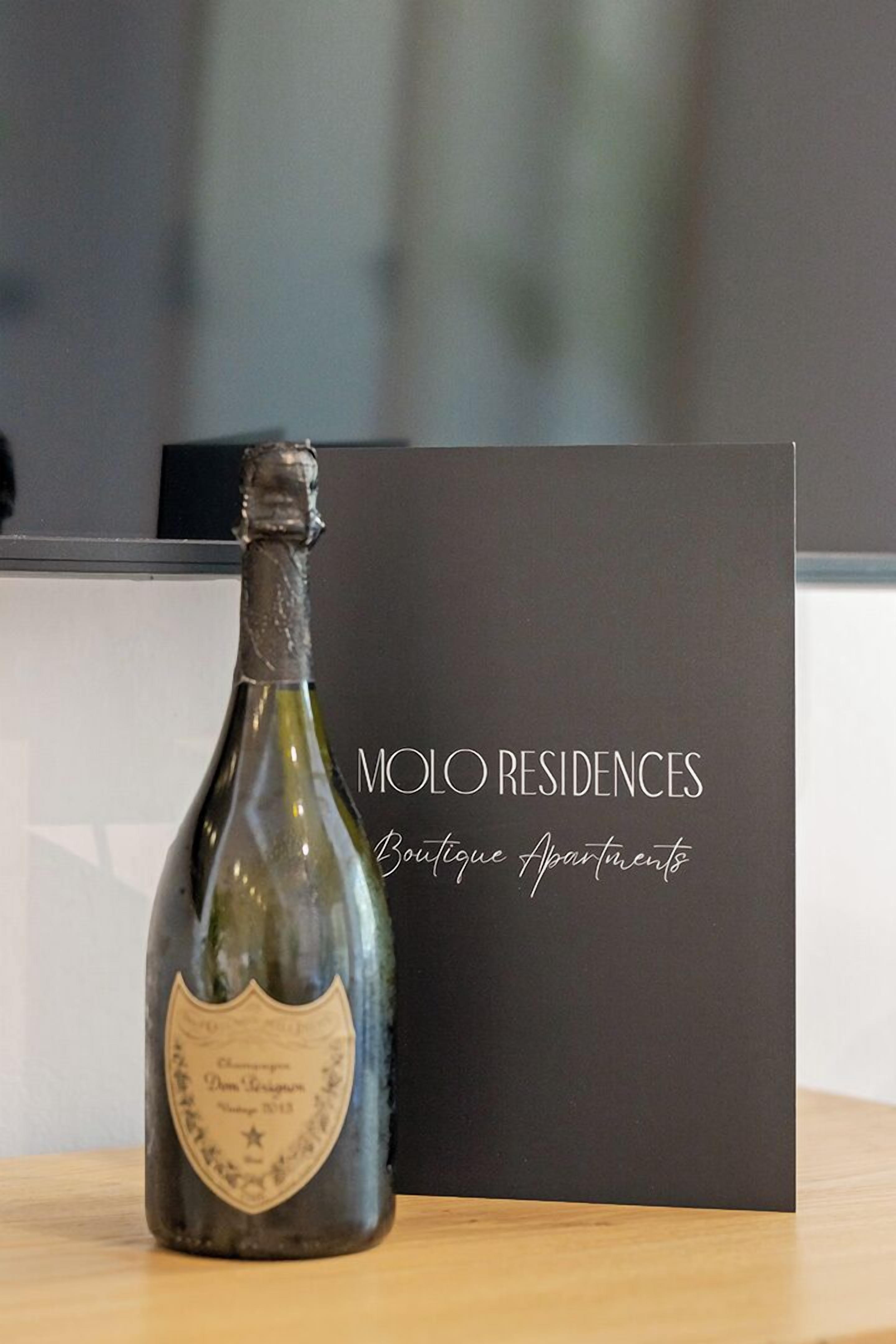 A bottle of champagne and a black card with 'MOLO RESIDENCES Boutique Apartments' written on it.