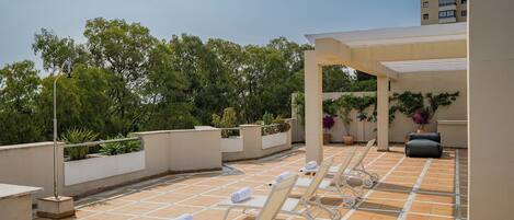 Une terrasse sur le toit, avec des chaises longues et des plantes en pot.