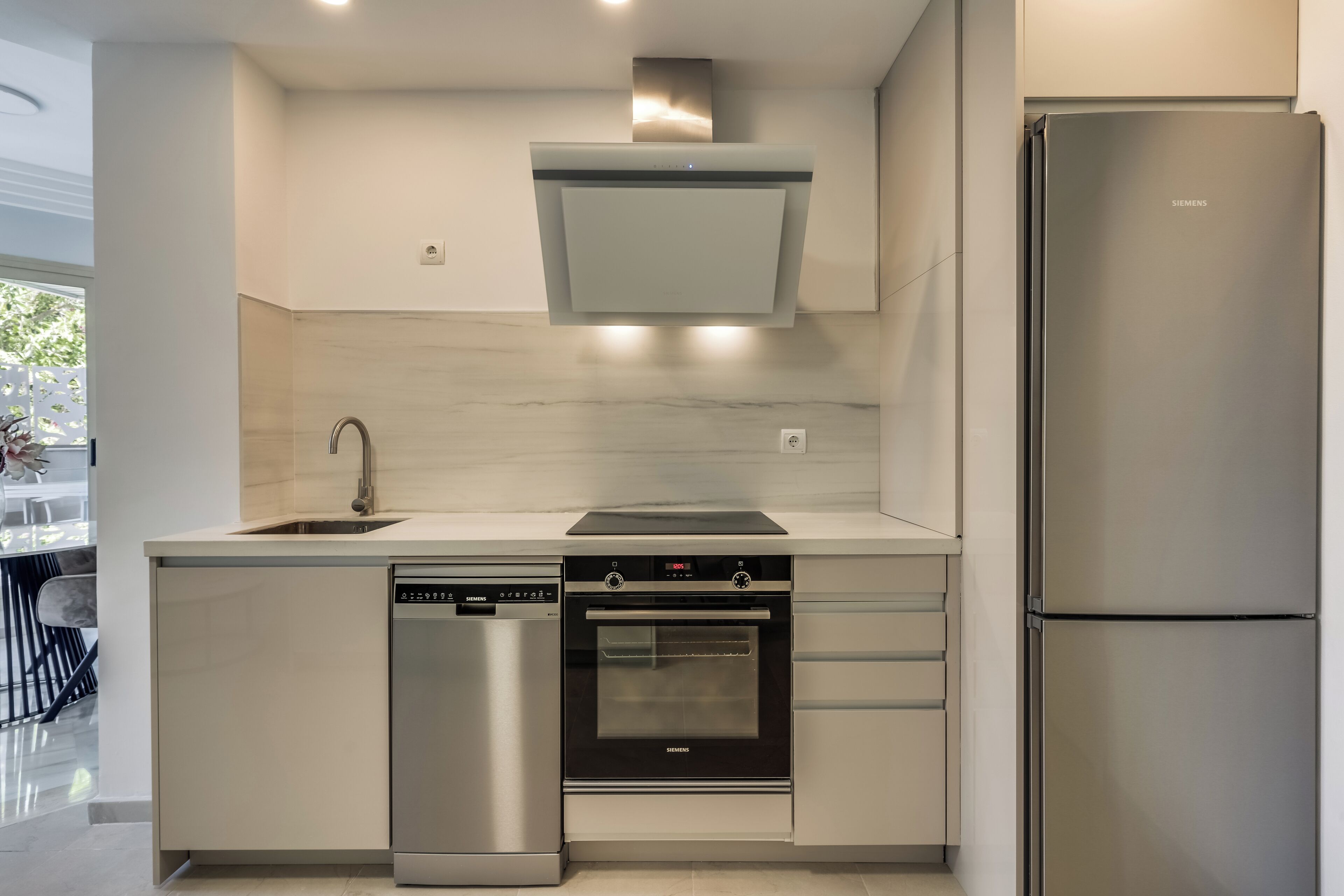Eine moderne Küche mit Geschirrspüler, Backofen und Kühlschrank.