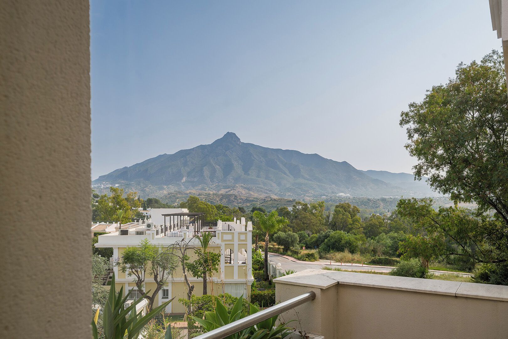 Une vue sur la montagne depuis un balcon, avec un bâtiment au premier plan.