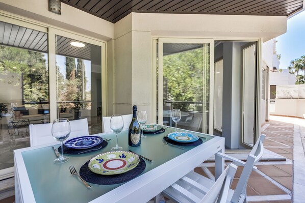 A dining area with a glass table set for four, featuring blue and green plates, wine glasses, and a bottle. - Molo Residences Boutique Apartment & Spa (Marbella)