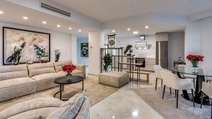 Un salon moderne comprenant un canapé, une table basse et un coin repas avec des chaises et une table en verre.