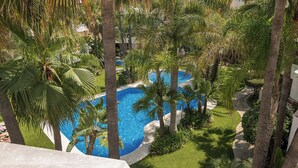 Une piscine entourée de palmiers et de verdure, offrant une vue dégagée sur les bords de la piscine et la végétation environnante.