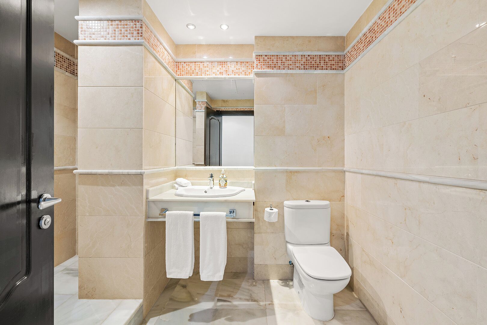 Un baño con lavamanos, inodoro y dos toallas colgadas en la pared.