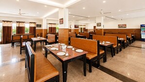 Un restaurante espacioso con techos altos, varias zonas de comedor y una máquina expendedora.