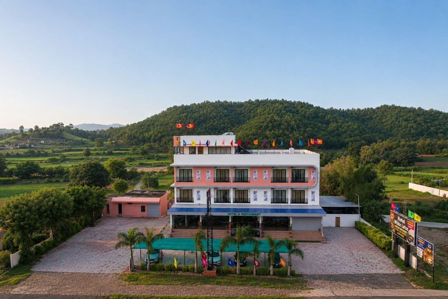 Un hotel de varios pisos con techo plano, entrada cubierta y vistas a un paisaje montañoso.