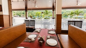 Un restaurante con una mesa larga dispuesta para cuatro personas, vistas al exterior y un ventilador de techo.