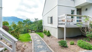A two-story house with a covered porch, a stone pathway, and a view of mountains. - Top of 7, B-10- Close to Boone & Banner Elk, Mtn View, Fireplace, Cute & quaint (Seven Devils)