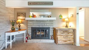 A cozy living room with a fireplace, a wooden table with a vase, and a sign above the fireplace reading "WELCOME TO THE MOUNTAINS". - Top of 7, B-10- Close to Boone & Banner Elk, Mtn View, Fireplace, Cute & quaint (Seven Devils)