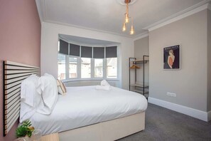 A bedroom with a large bed, a curved window, a shower, and a wall-mounted light fixture.