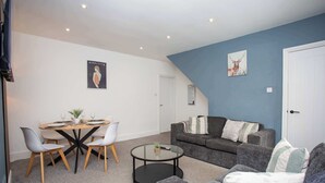 Una sala de estar moderna con comedor, un sofá gris y un cuadro en la pared.