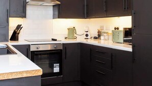 Una cucina moderna con mobili scuri, pavimento in legno a spina di pesce ed elettrodomestici in acciaio inossidabile.