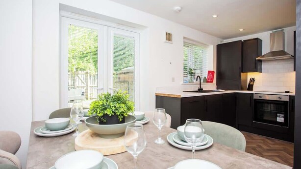 Una cucina moderna con mobili scuri, forno integrato e vista su un'area verde.