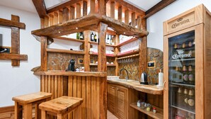 Eine rustikale Küche mit Holzbarhocker, einer Steinrückwand und einem Corona-Kühlschrank.