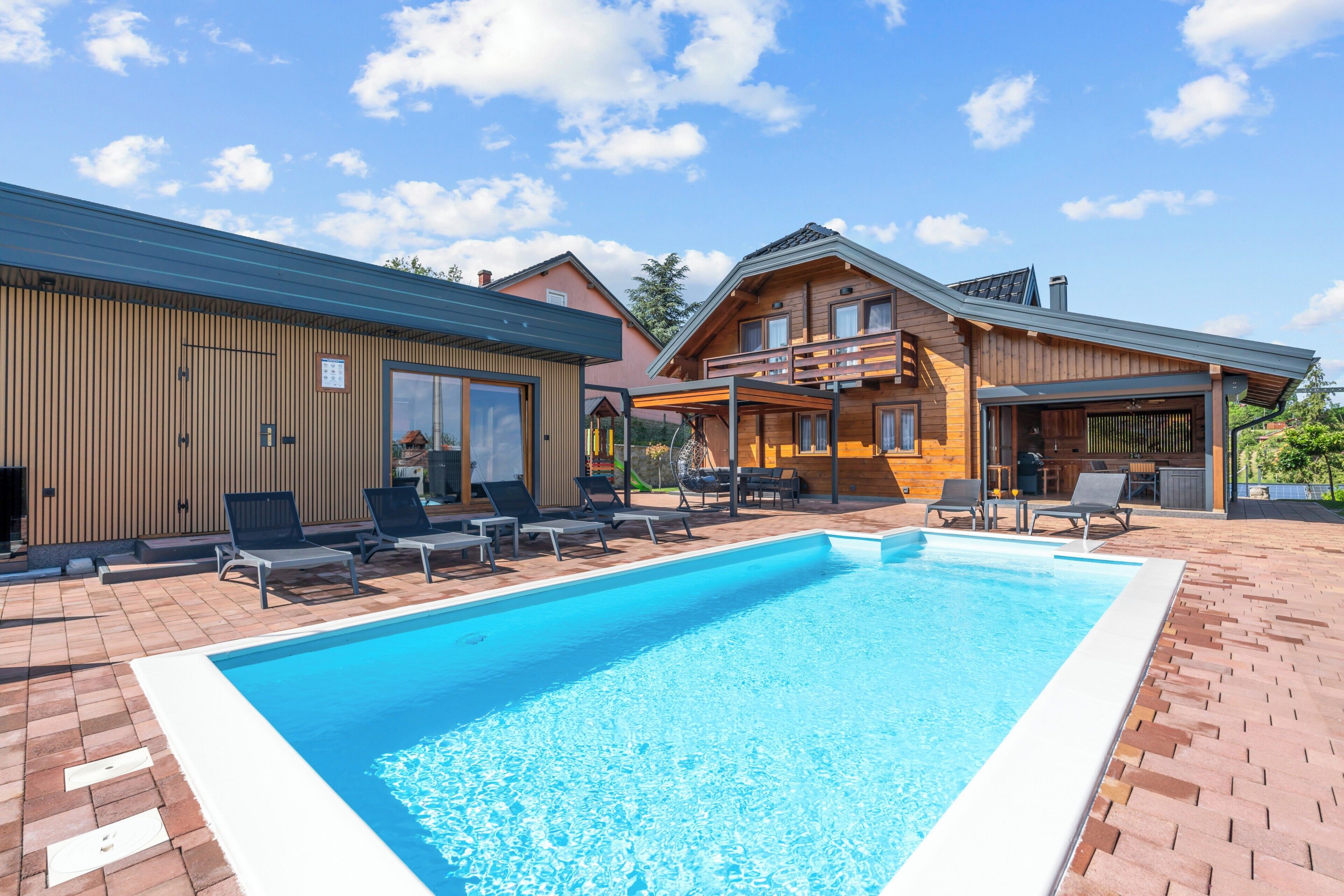 Een modern huis met een zwembad, buitenmeubels en een overdekt terras.