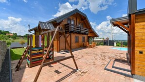 Eine Holzhütte mit Balkon, Schaukel und Schwimmbecken.