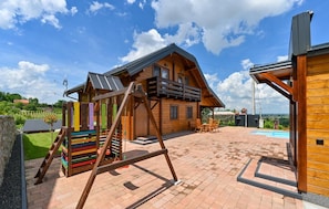 Una cabaña de madera con balcón, un columpio y una piscina.